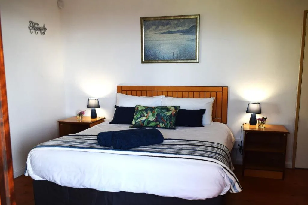 Spacious bedroom with queen bed, wooden headboard, and bedside lamps