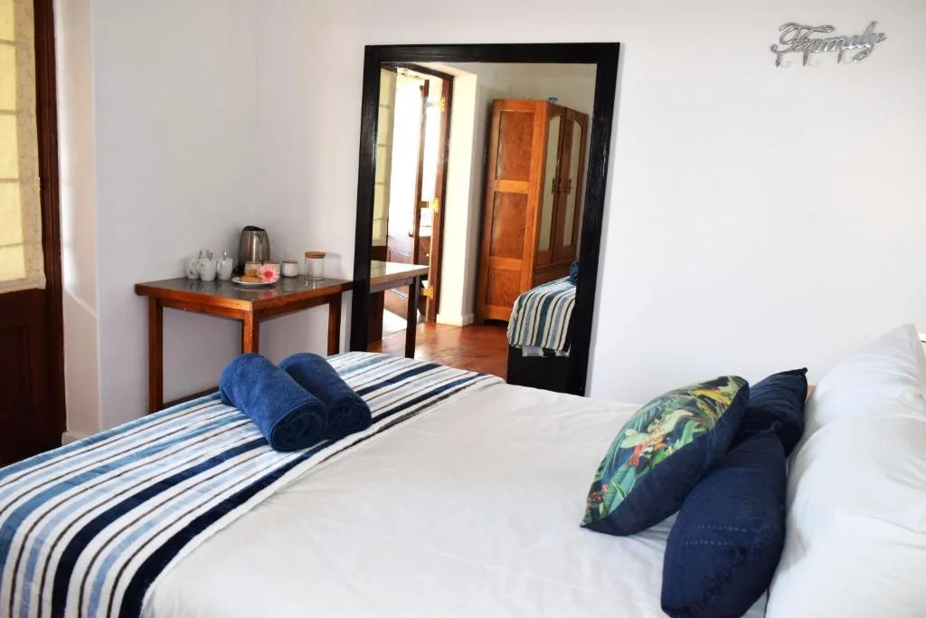 Bright bedroom with striped bedding, decorative pillows, wooden desk, and large mirror