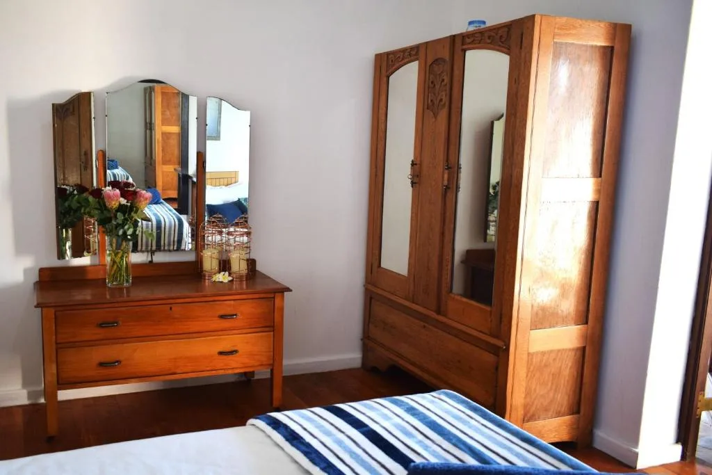 Bedroom with wooden dresser, mirror, wardrobe, and striped bedding