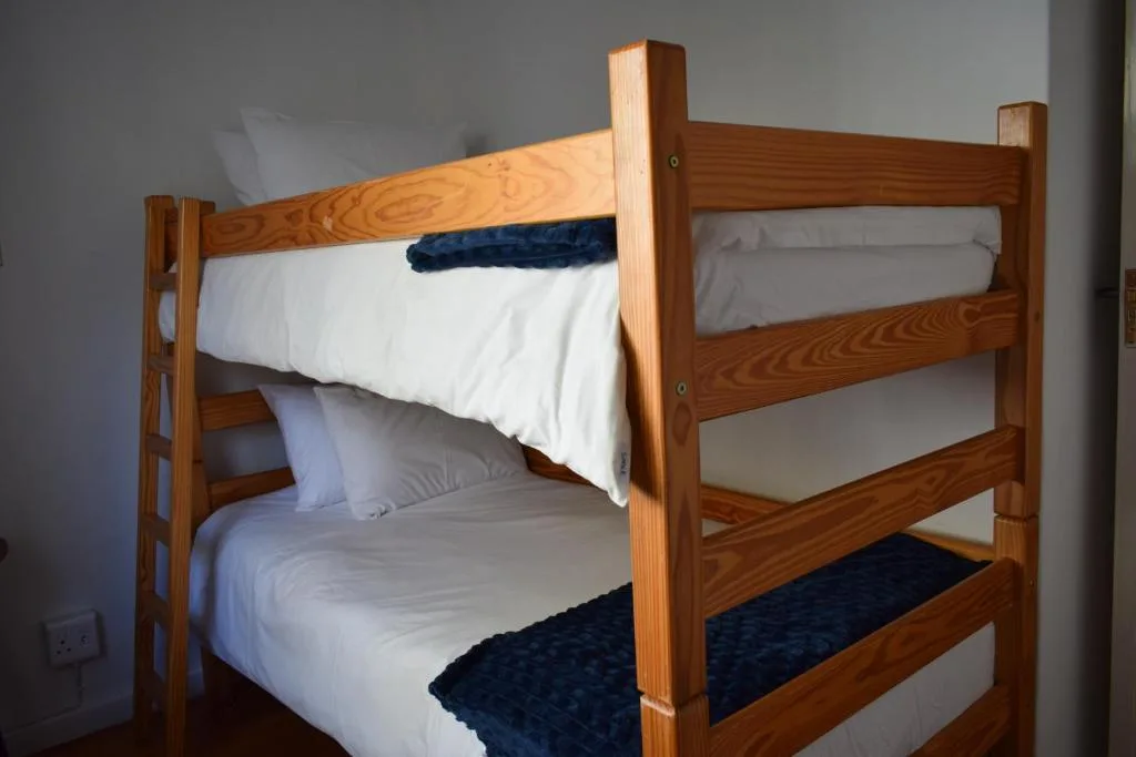 Wooden bunk bed with white sheets and navy blankets in bedroom