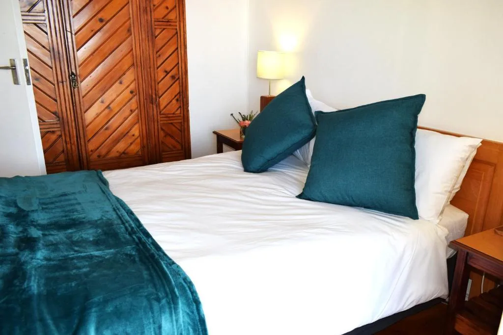 Spacious bedroom with white bedding and teal velvet pillows and throw
