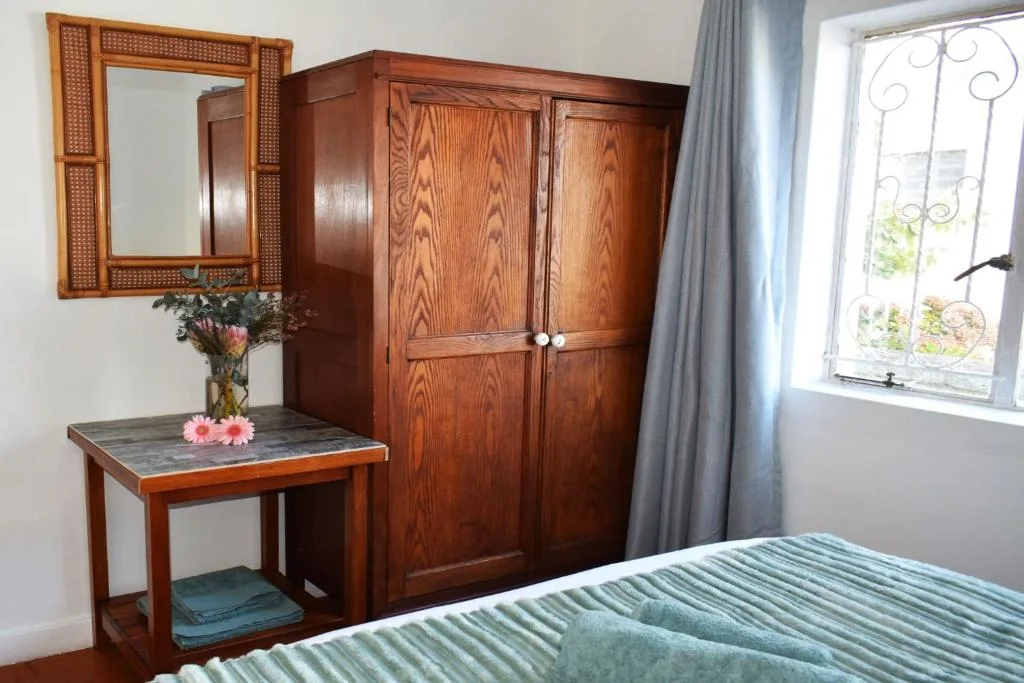 Bedroom with wooden wardrobe, vanity table, and striped bedding