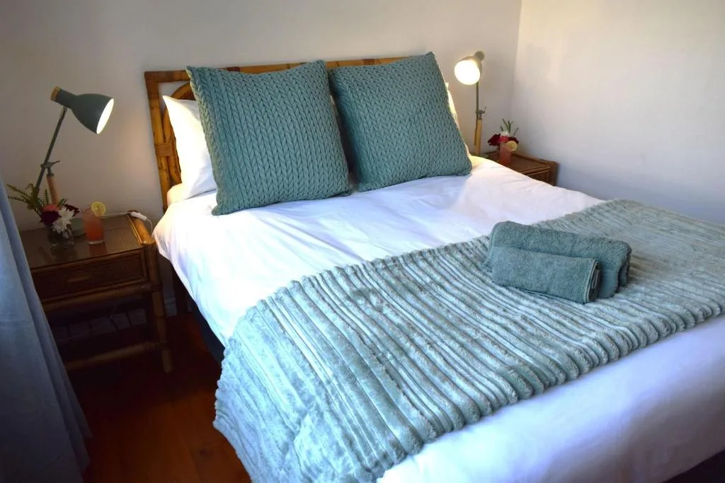 Neatly made bed with teal pillows and white linens in bedroom