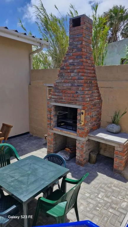Outdoor patio with brick fireplace, dining table, and garden views