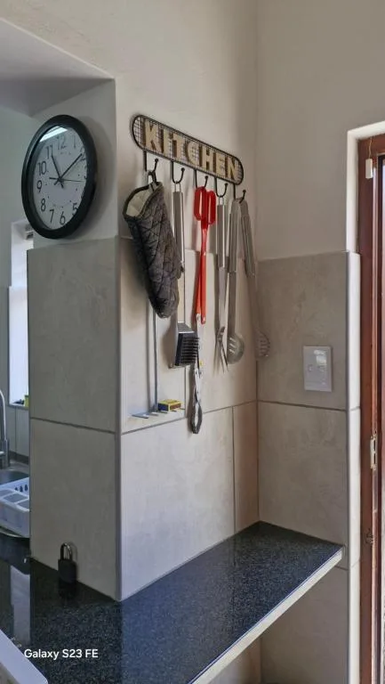 Kitchen wall with clock, utensil rack, and organized cooking tools