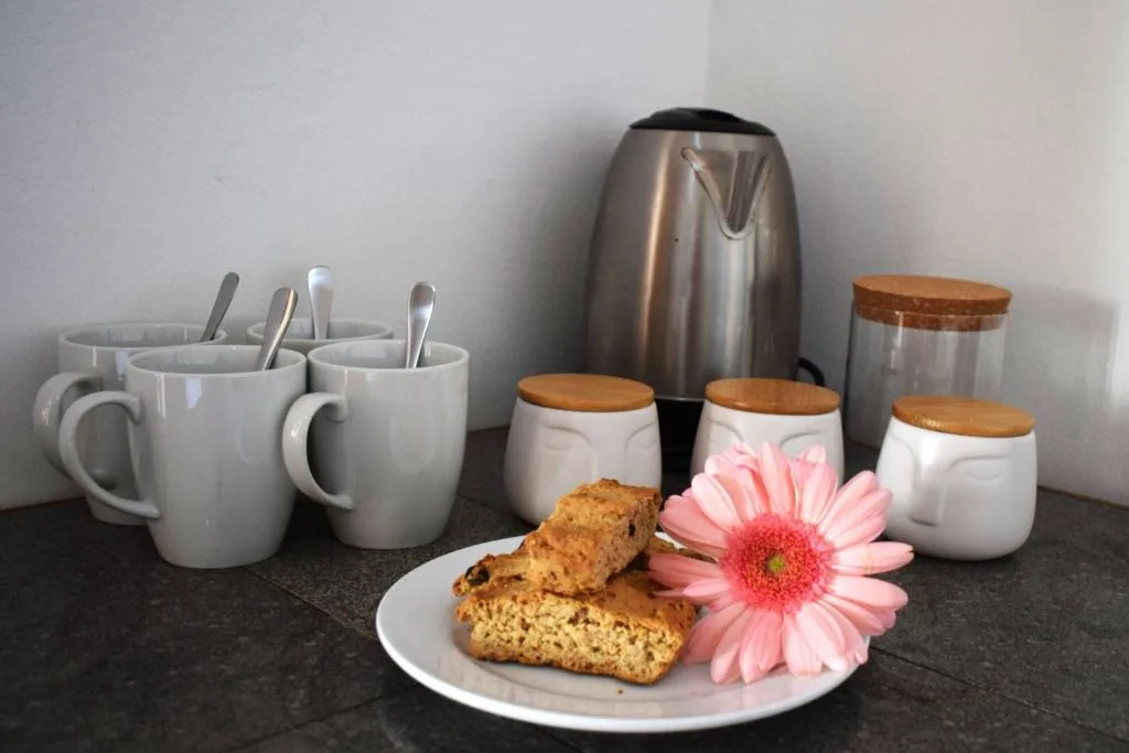 Kitchen counter display with mugs, kettle, storage jars, and baked goods