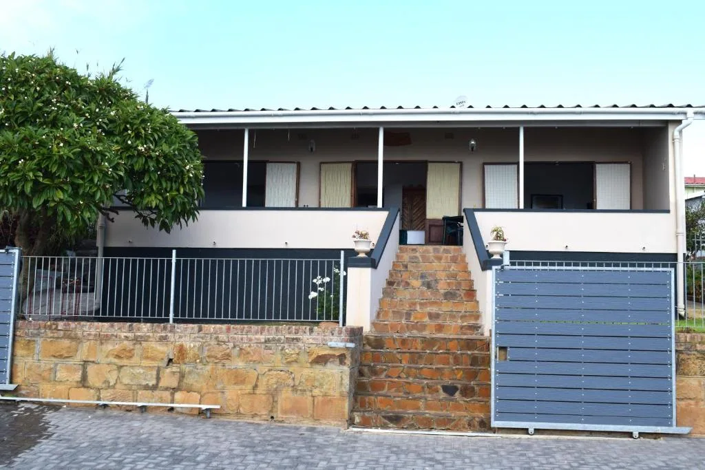 White and cream holiday home facade with brick steps and metal railings