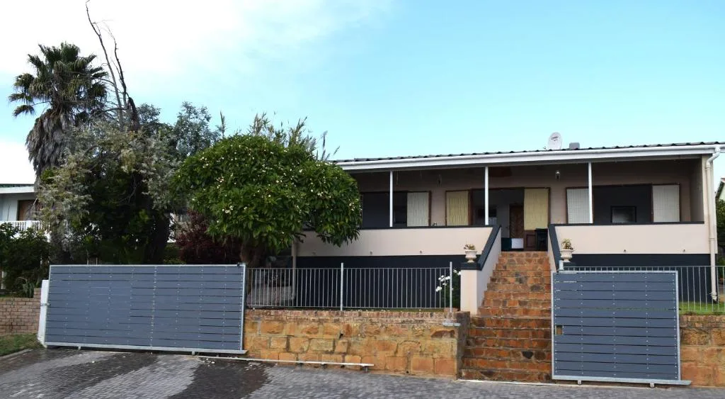 Modern single-story home with brick base, metal gates, and tropical landscaping