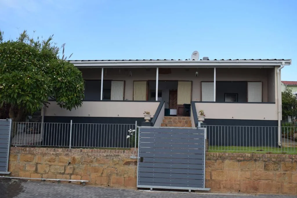 Modern single-story accommodation with elevated deck and metal railings, clear sky