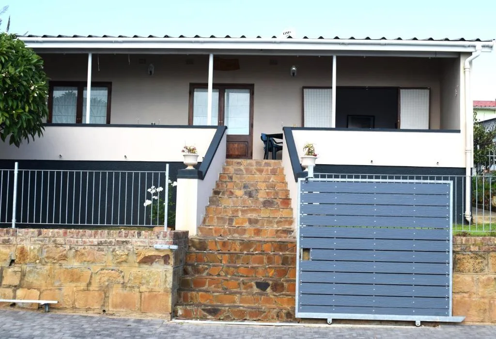 Modern white holiday home with covered porch and brick driveway entrance