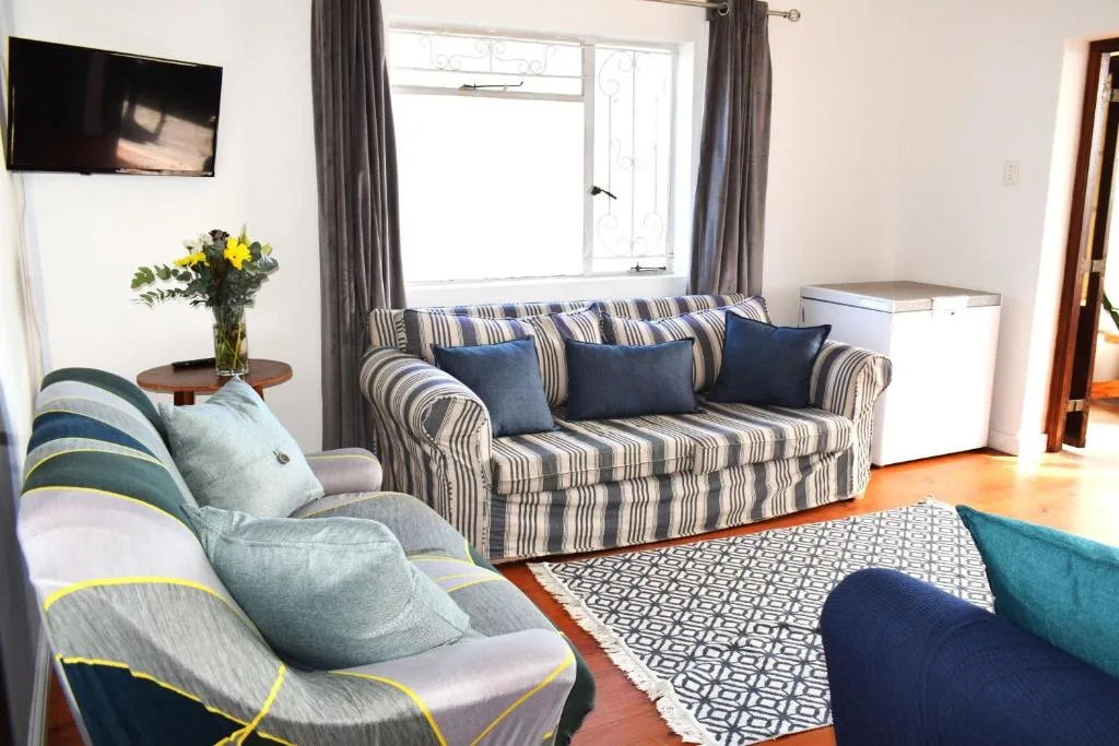 Bright lounge with striped sofa, armchairs, and wall-mounted television
