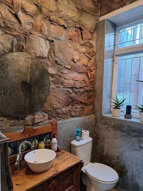 Rustic bathroom with stone wall, wooden vanity, and round sink