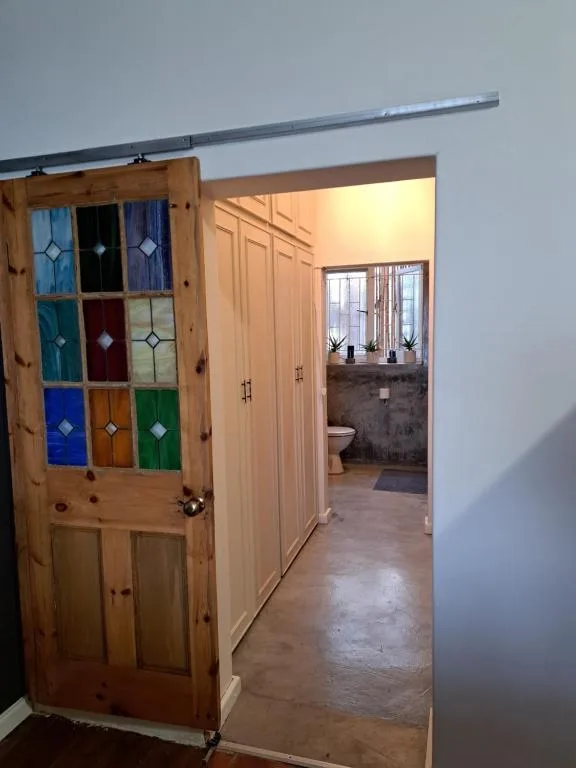 Wooden door with colorful stained glass panels and bathroom view beyond