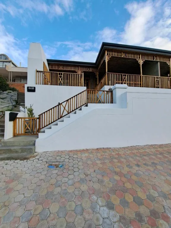 Modern white house with wooden deck railings and brick driveway entrance
