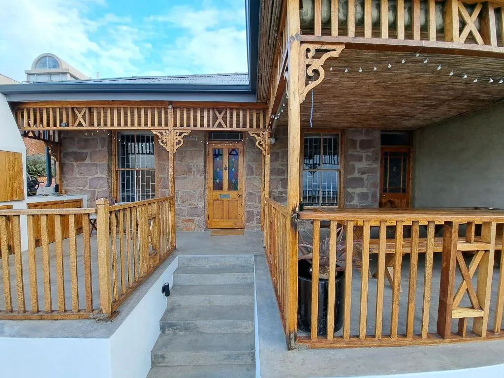 Stone and timber cottage with wooden verandas and decorative railings