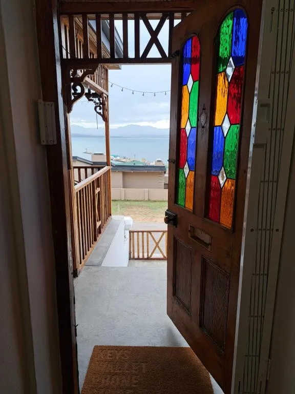 Ocean and mountains visible through open doorway with colorful stained glass decoration