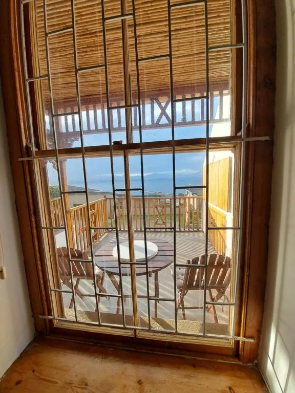 Scenic coastal view through glass doors with ocean horizon and deck seating visible