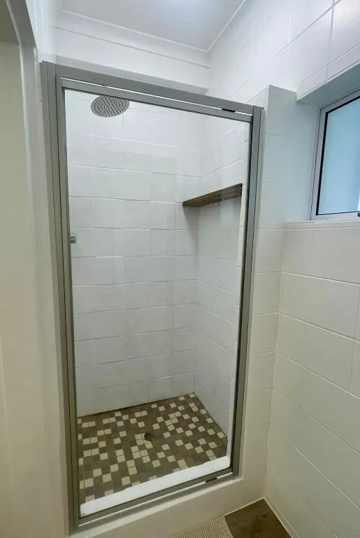 Modern shower enclosure with glass door and rainfall showerhead