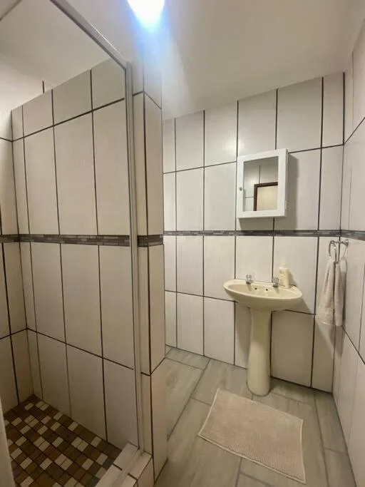 Clean bathroom with pedestal sink, tiled shower enclosure, and mirror