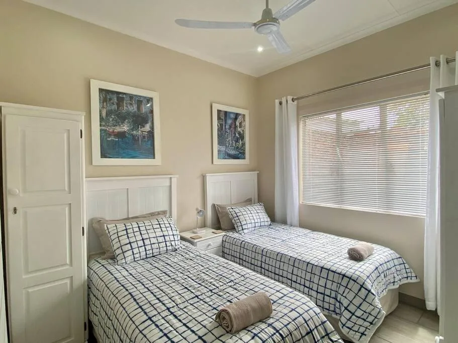 Twin bedroom with checkered bedding, white headboards, and framed artwork
