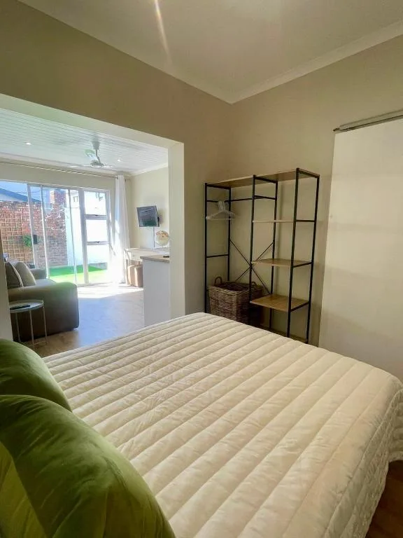 Bright bedroom with queen bed, green cushions, and open patio access