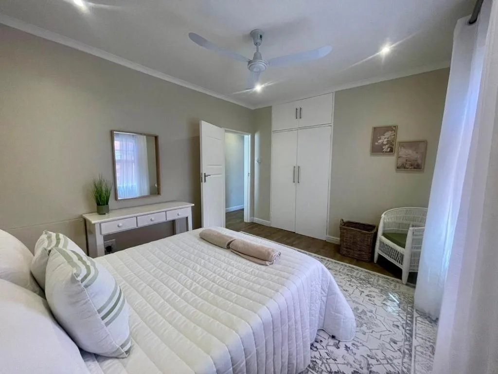 Spacious bedroom with queen bed, white wardrobe, and vanity mirror