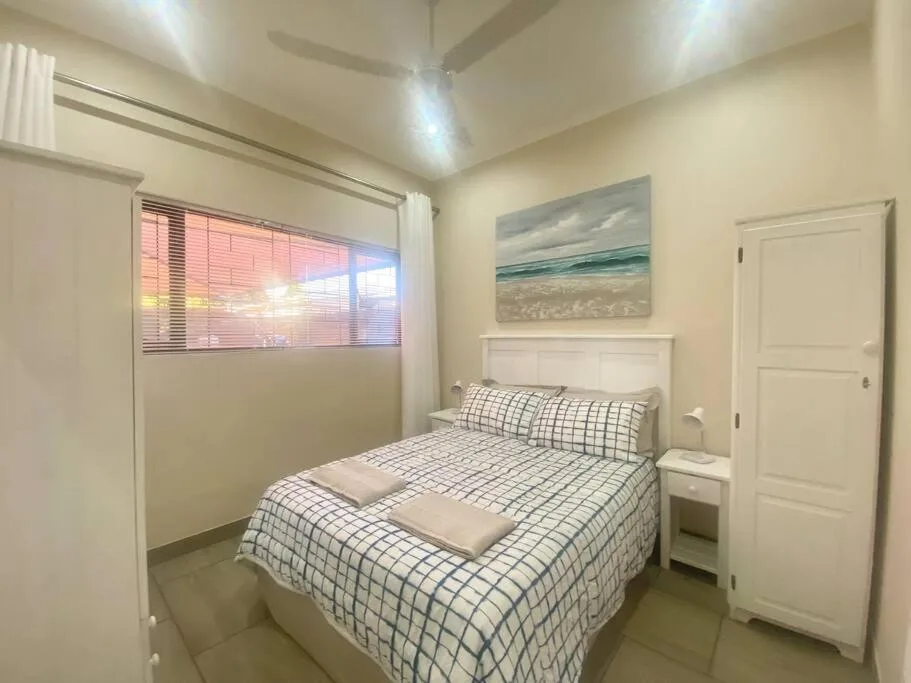 Bright bedroom with neatly made bed and coastal artwork on walls