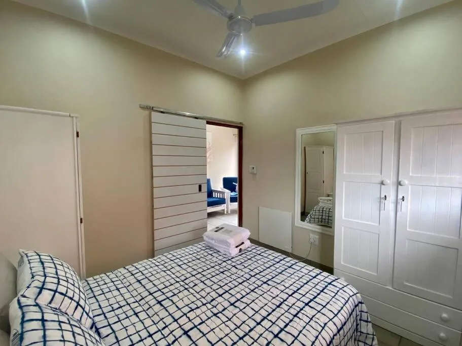 Bright bedroom with queen bed, built-in wardrobes, and modern ceiling fan