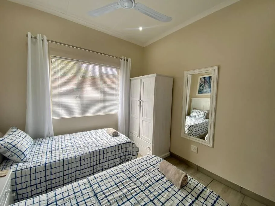 Bright bedroom with two single beds and white wardrobe storage