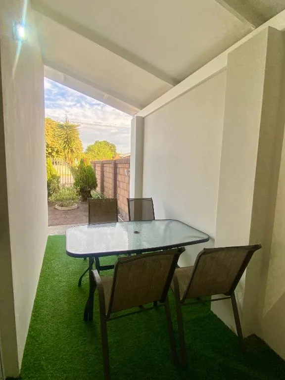 Covered outdoor patio with dining table and chairs overlooking garden