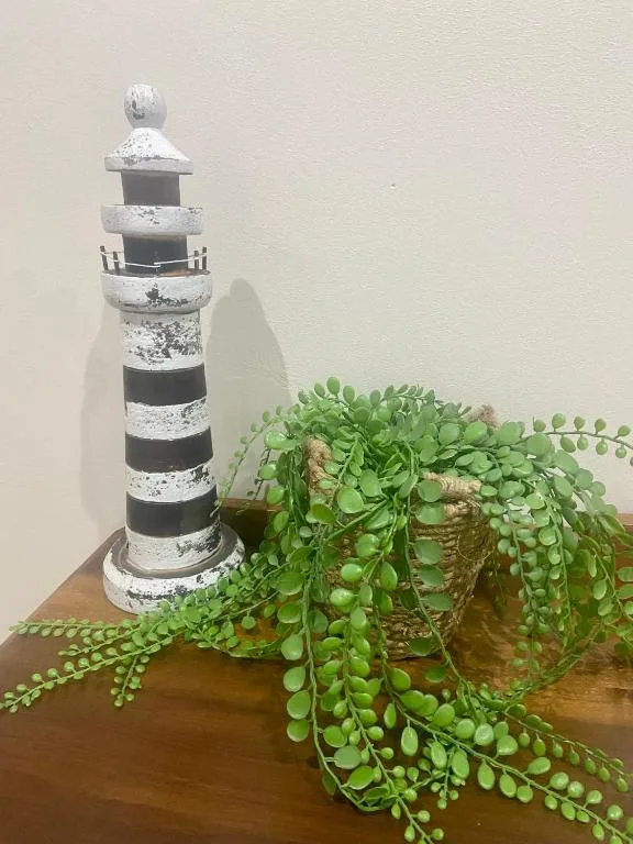 Decorative lighthouse model with striped pattern and trailing green plant