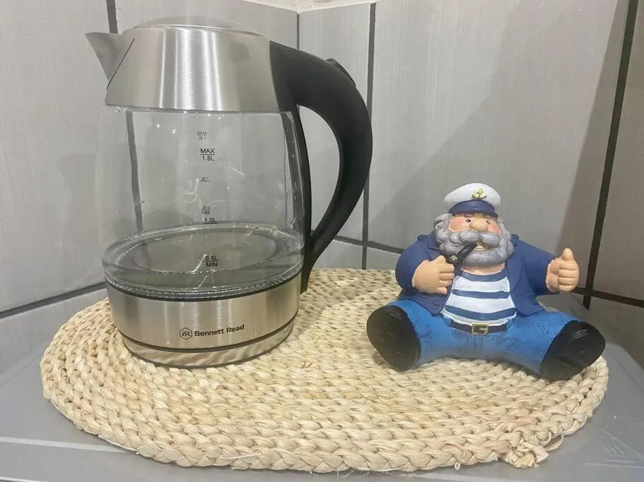 Electric kettle and decorative sailor figurine on woven placemat