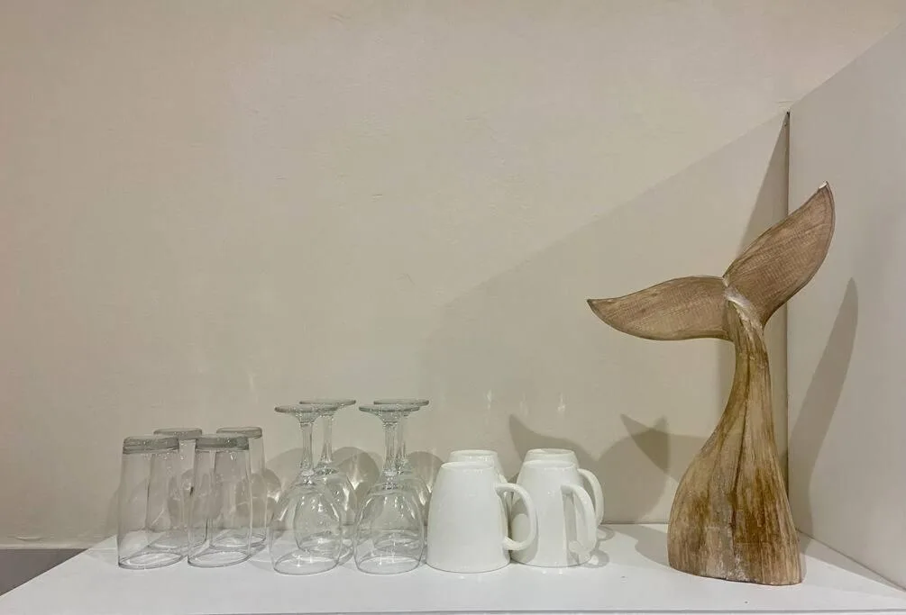 Decorative tabletop display with glassware, mugs, and wooden whale sculpture