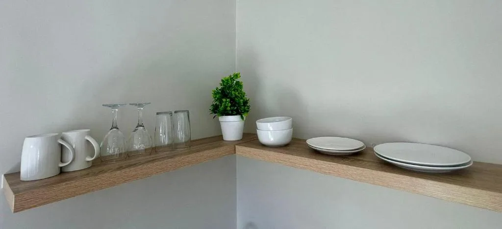 Kitchen shelf with dishes, glasses, mugs, and decorative potted plant