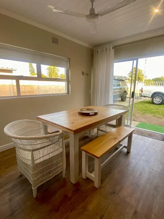 Wooden dining table with woven chairs overlooking garden and driveway
