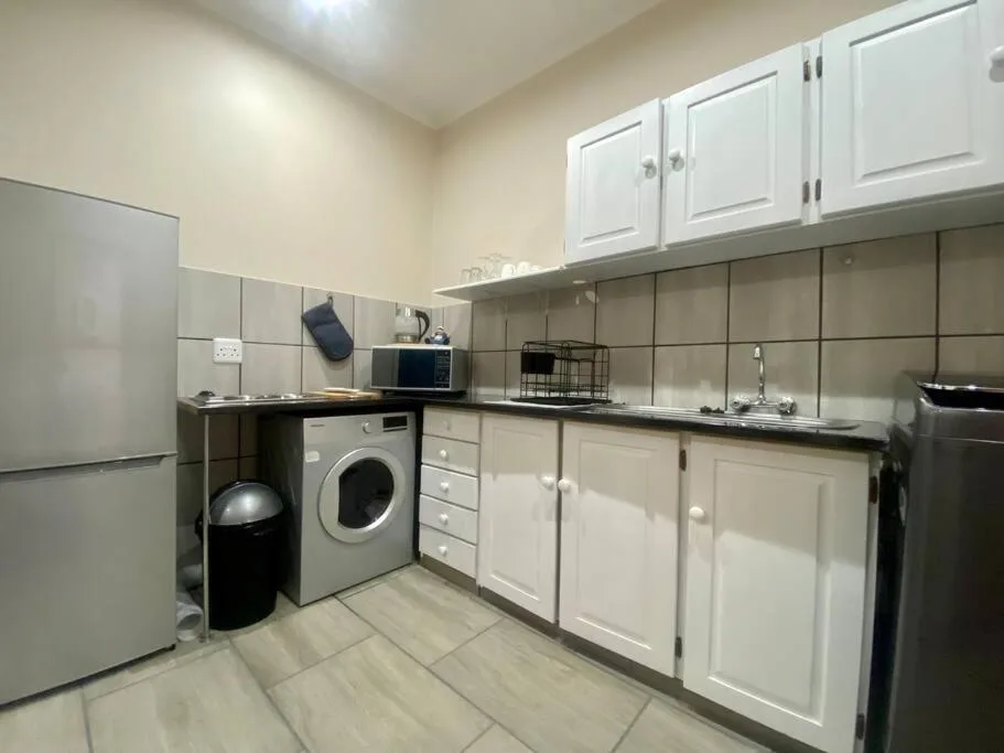 Modern kitchen with white cabinetry, stainless steel appliances, and washing machine