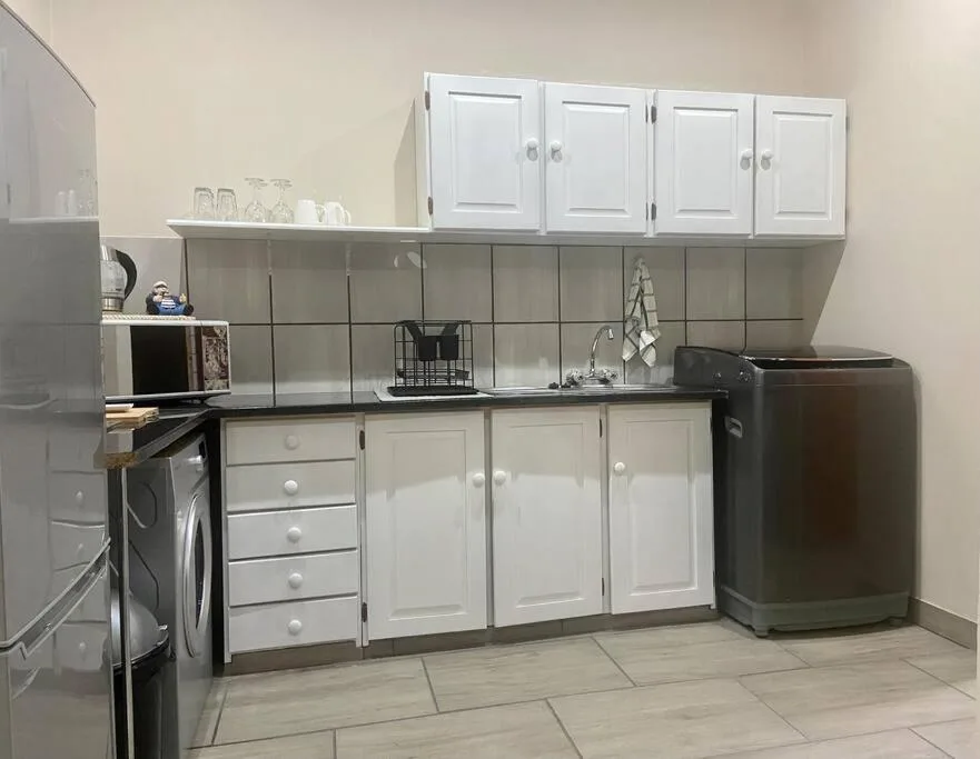 Modern kitchen with white cabinetry, black appliances, and tiled countertops