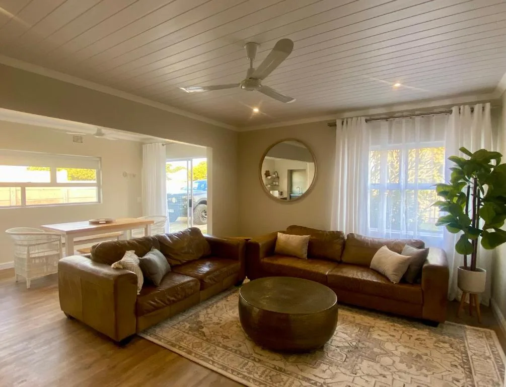 Spacious living room with brown leather sectional sofa and round ottoman
