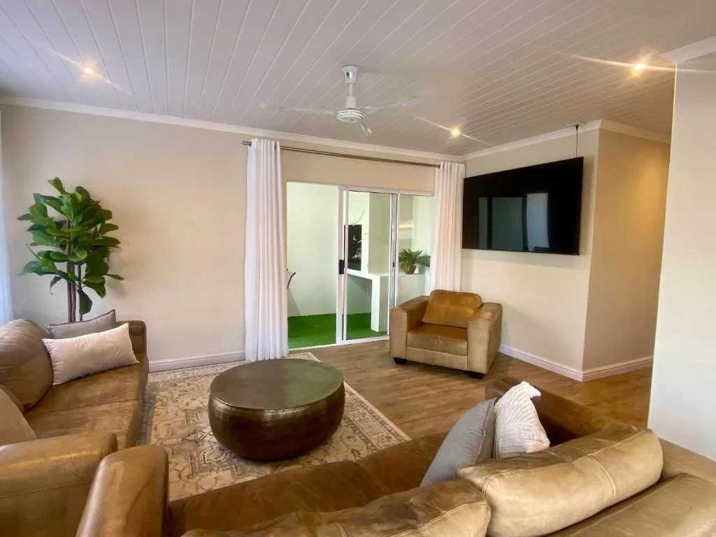 Modern lounge with leather seating, TV, and sliding doors to garden