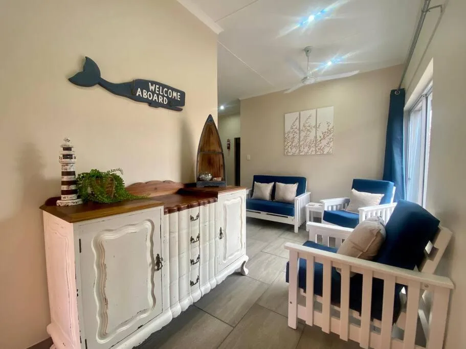 Nautical-themed lounge with blue seating, white furniture, and coastal decor