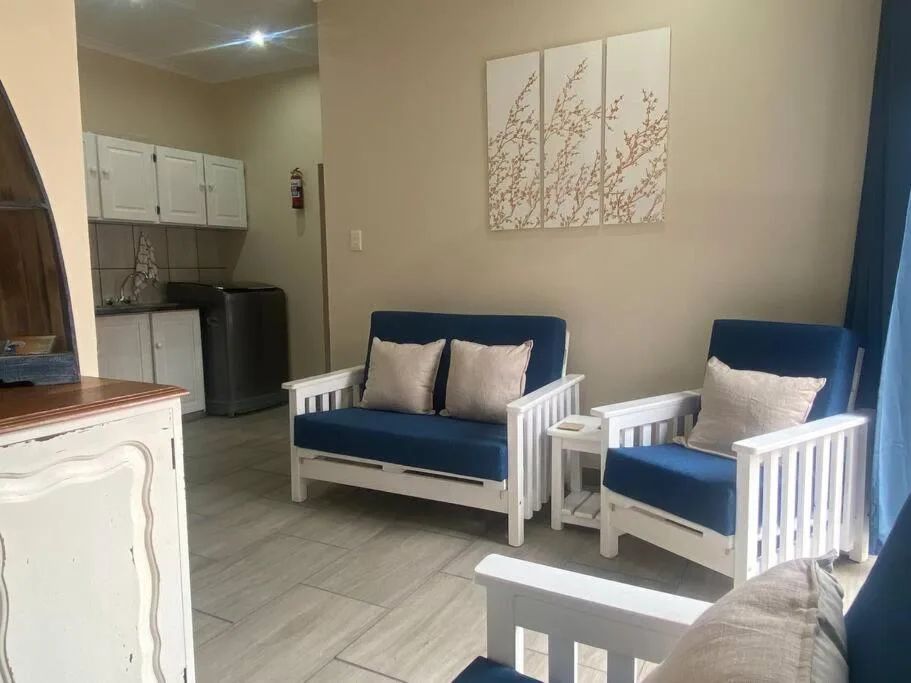 Open-plan lounge with blue sofas and white wooden frames, neutral decor