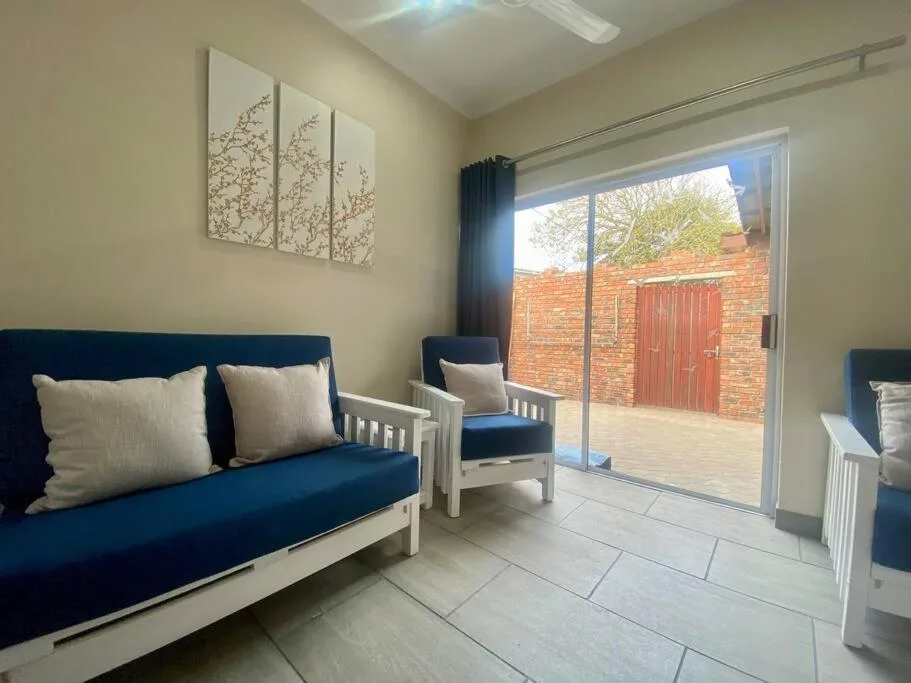 Bright lounge with blue sofa, wall art, and sliding glass doors opening to patio