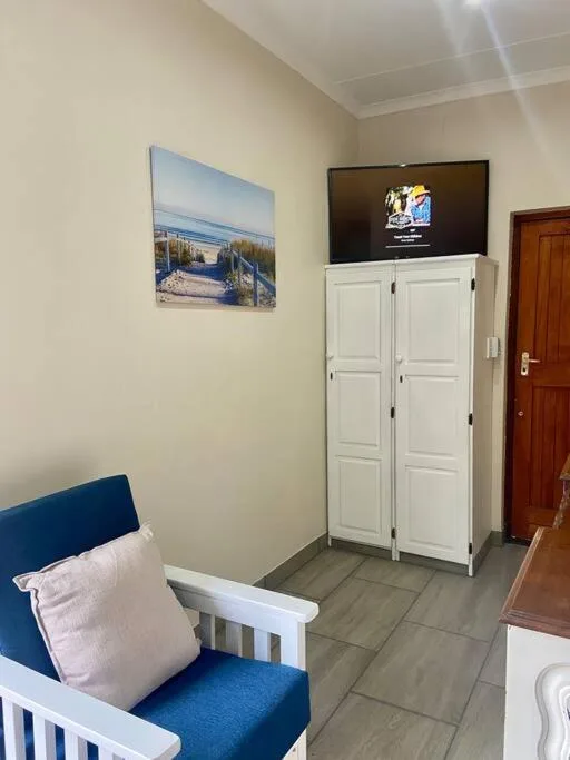 Compact living room with blue armchair, wall-mounted TV, and storage cabinet
