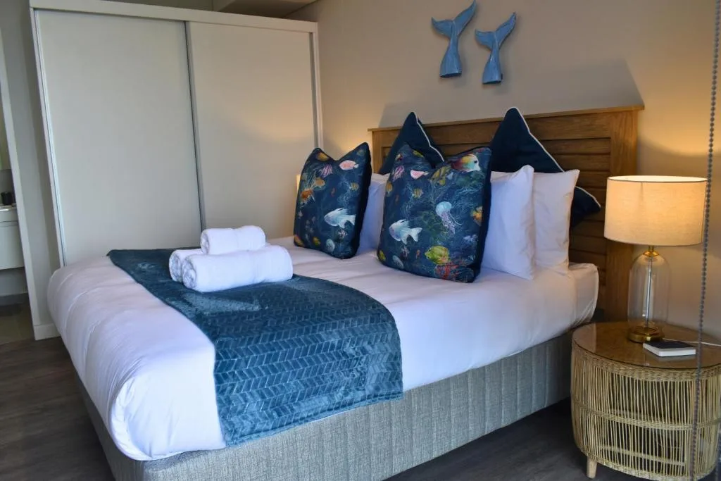Coastal-themed bedroom with ocean-print pillows and whale wall art