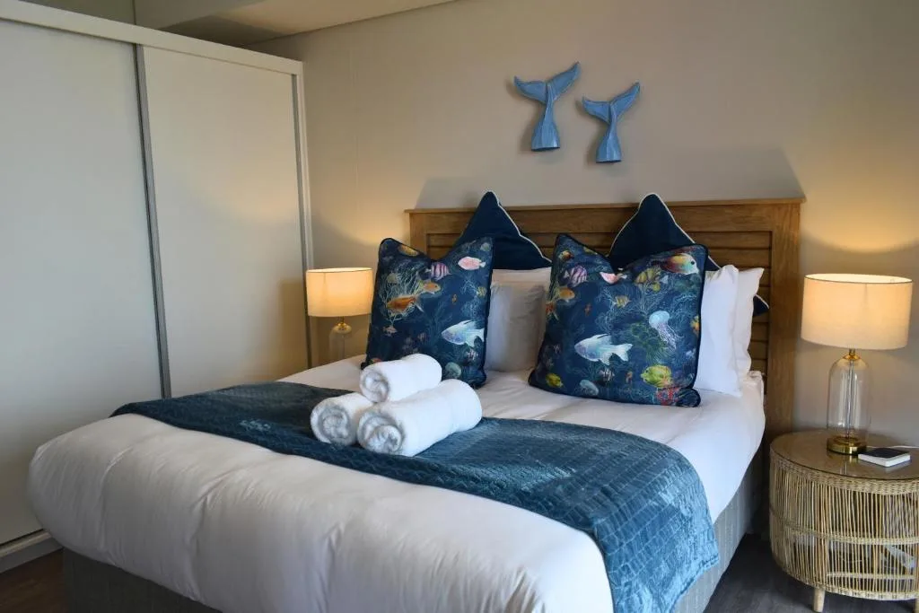 Coastal-themed bedroom with fish-print pillows and whale tail wall decor