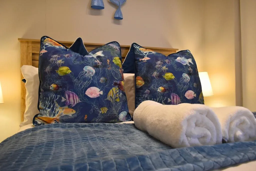 Bed with colorful fish-patterned pillows and rolled white towels