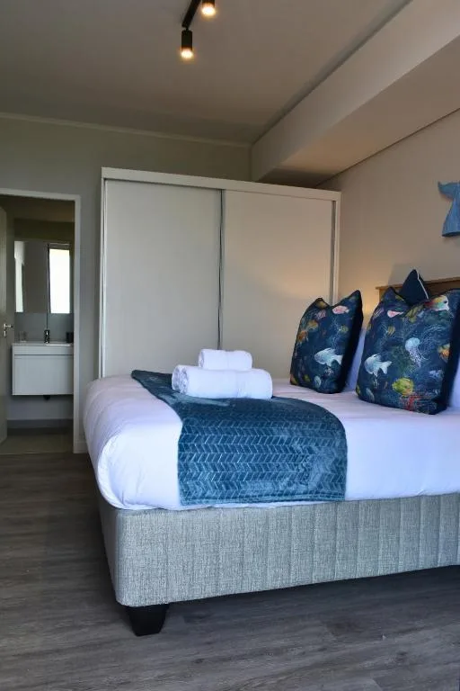 Spacious bedroom with neatly made bed and ocean-themed decorative pillows