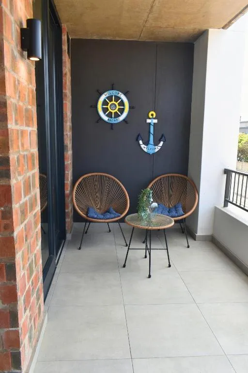 Sheltered patio with two woven chairs and nautical wall decorations