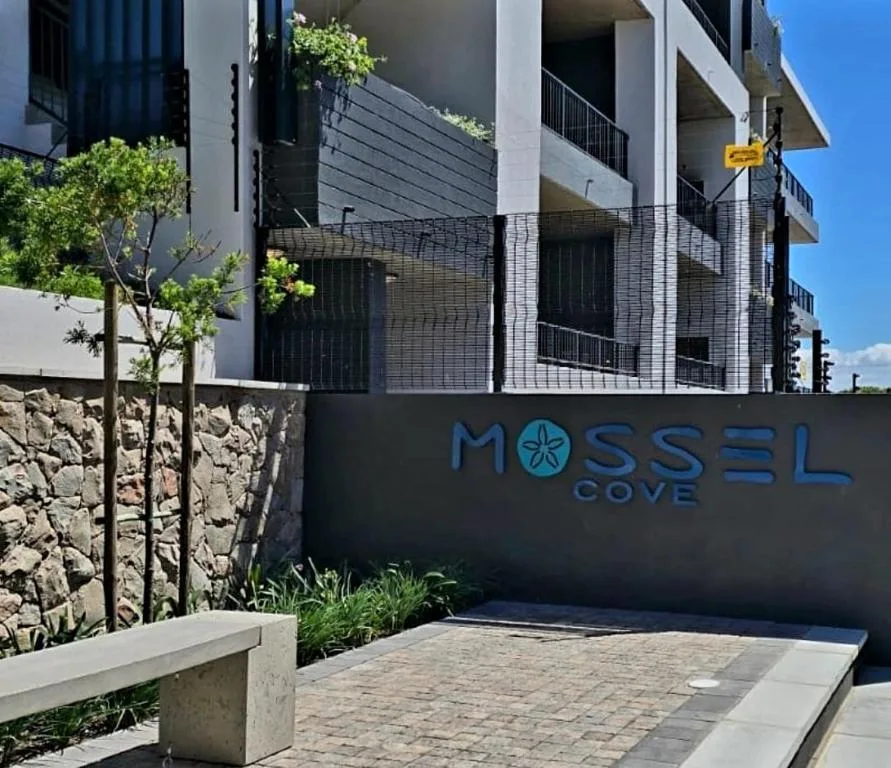Modern apartment building entrance with signage and paved driveway
