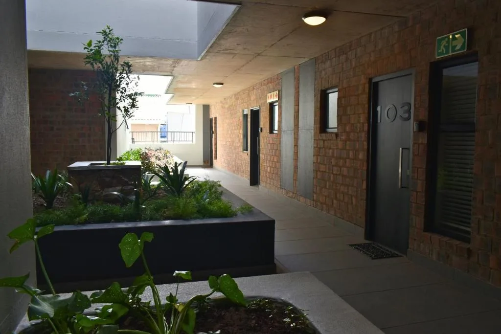 Modern apartment building entrance with brick facade and planted courtyard